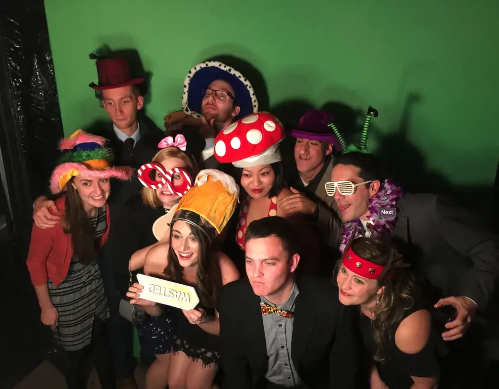 Group of guests with props in front of a green backdrop