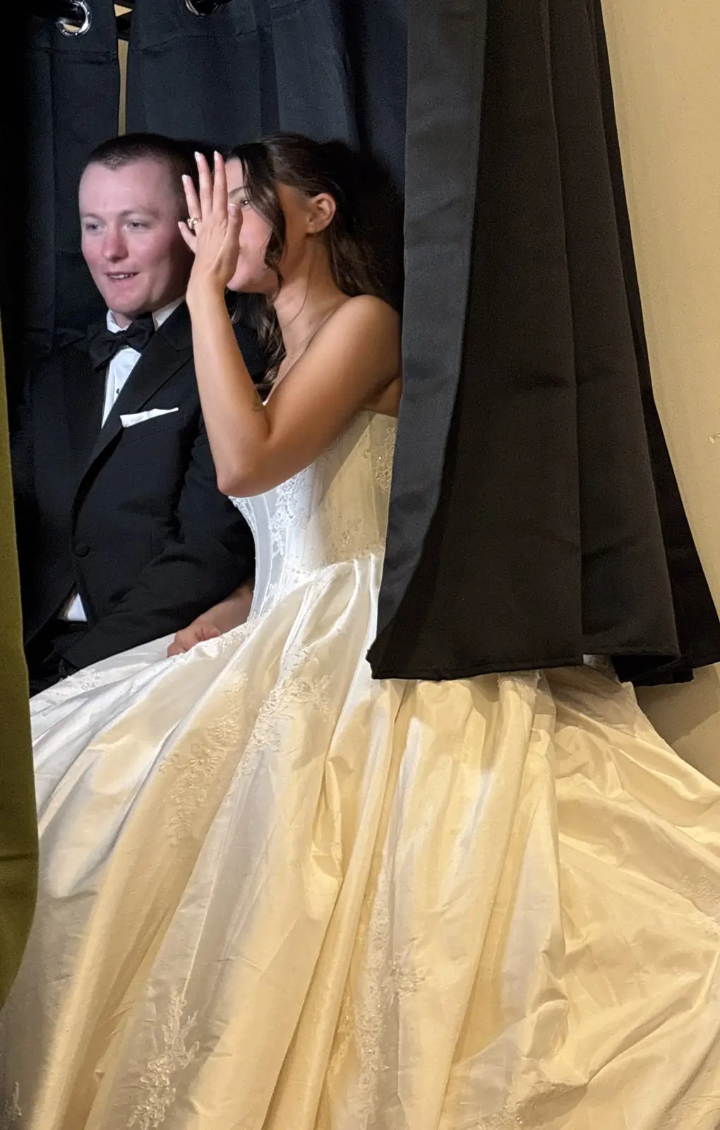 Bride and groom sitting inside the MojoHaus enclosed photo booth with the curtain drawn