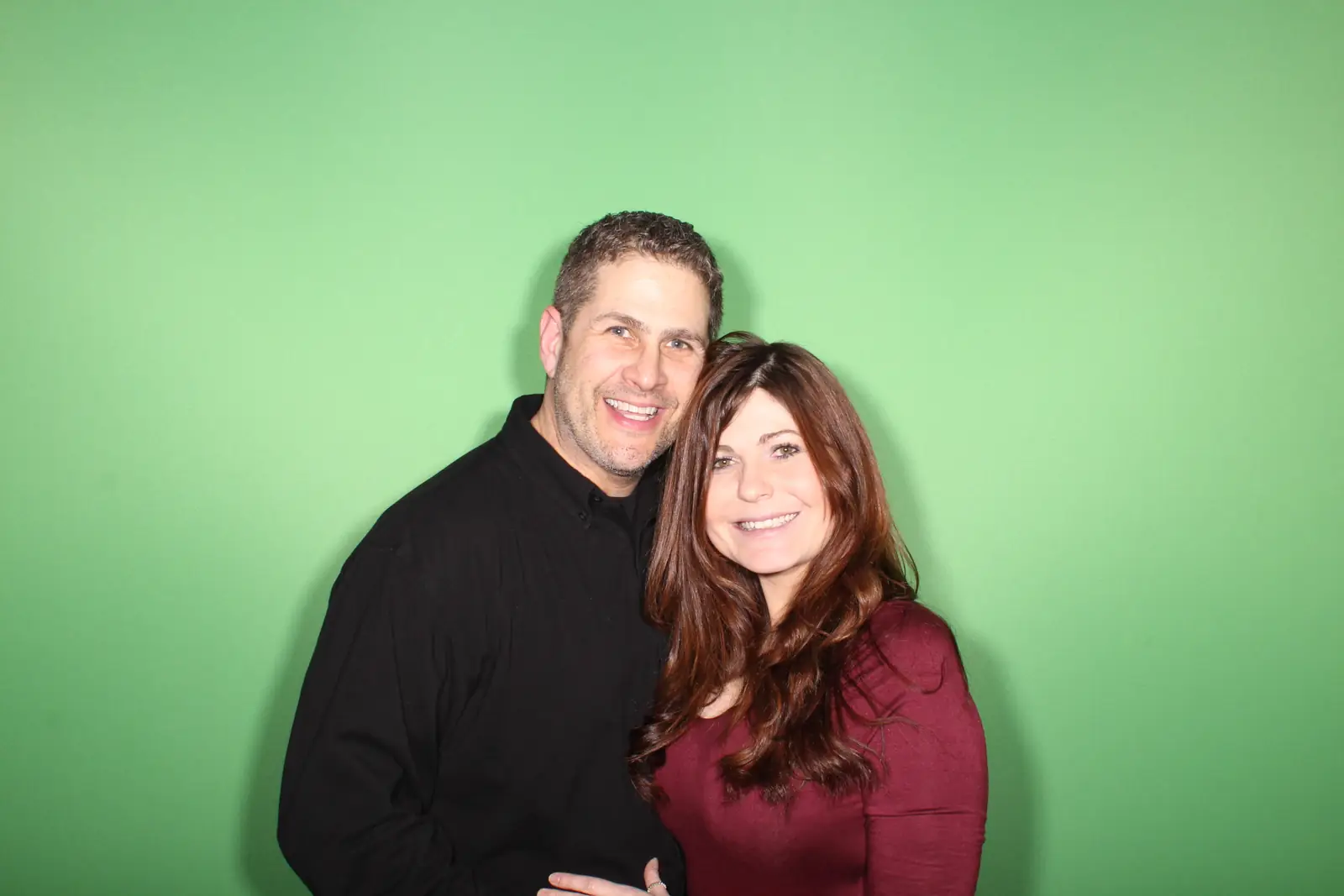 A couple photographed against the plain green screen backdrop in the MD Mojo booth, before any background is composited in