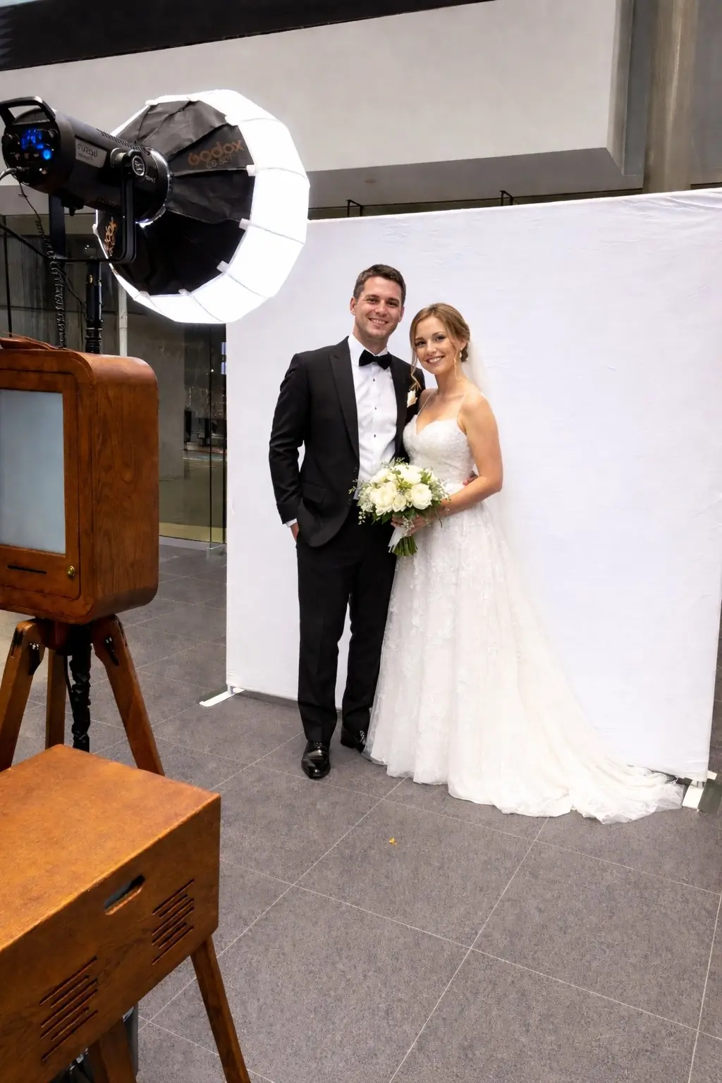 A couple posing at the Ikonic vintage photo booth against a plain white backdrop