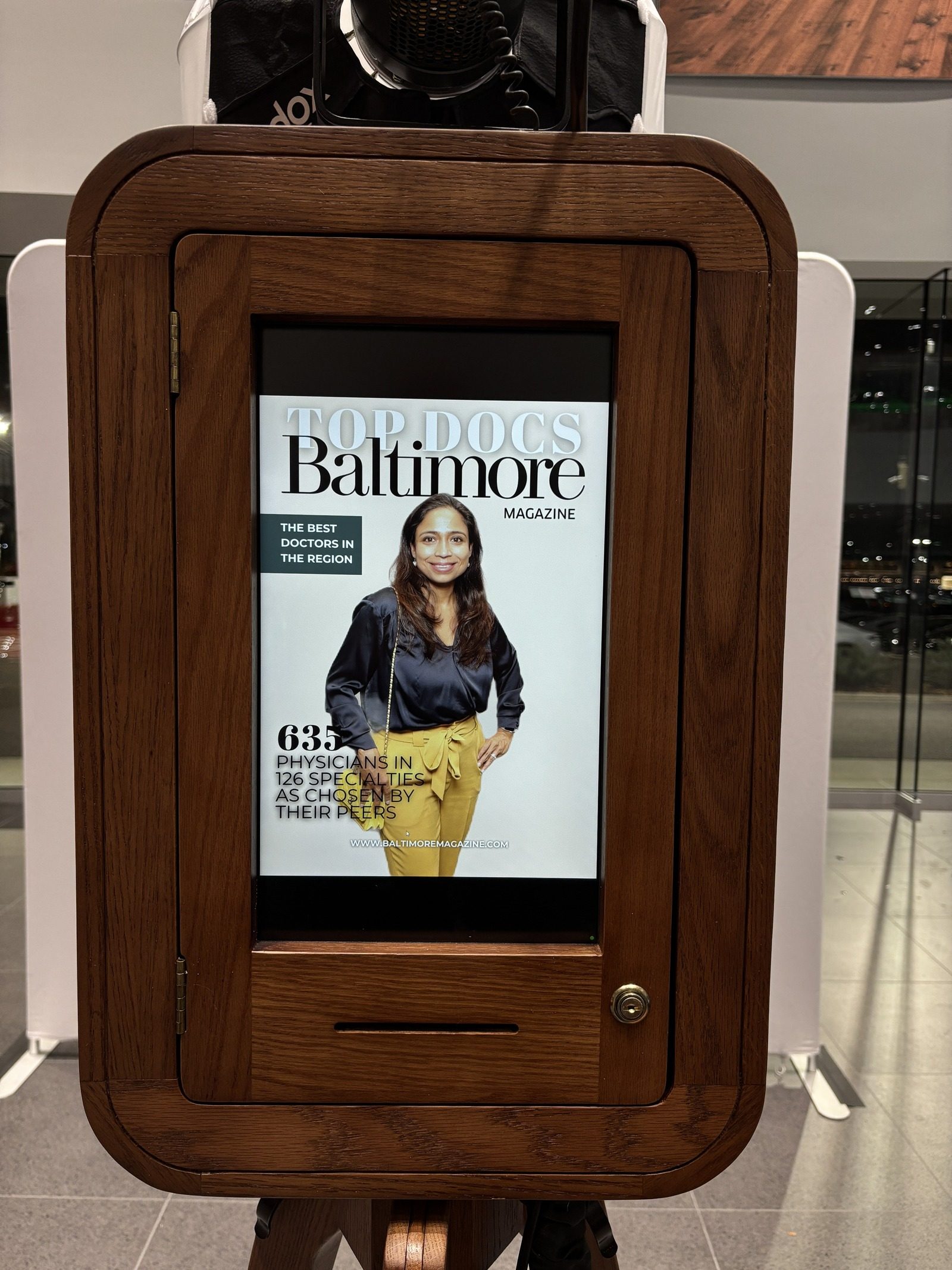 A finished cover shown on the booth screen in its wooden cabinet at a Baltimore Magazine Top Doctors event