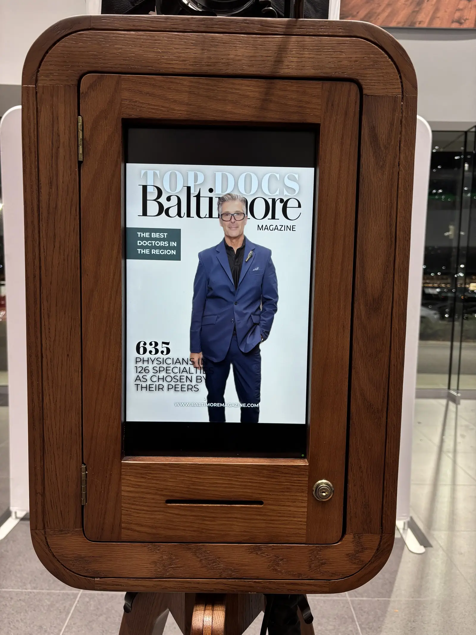 A finished cover displayed on the screen of an MD Mojo booth in a wooden cabinet, ready for the guest to approve before printing